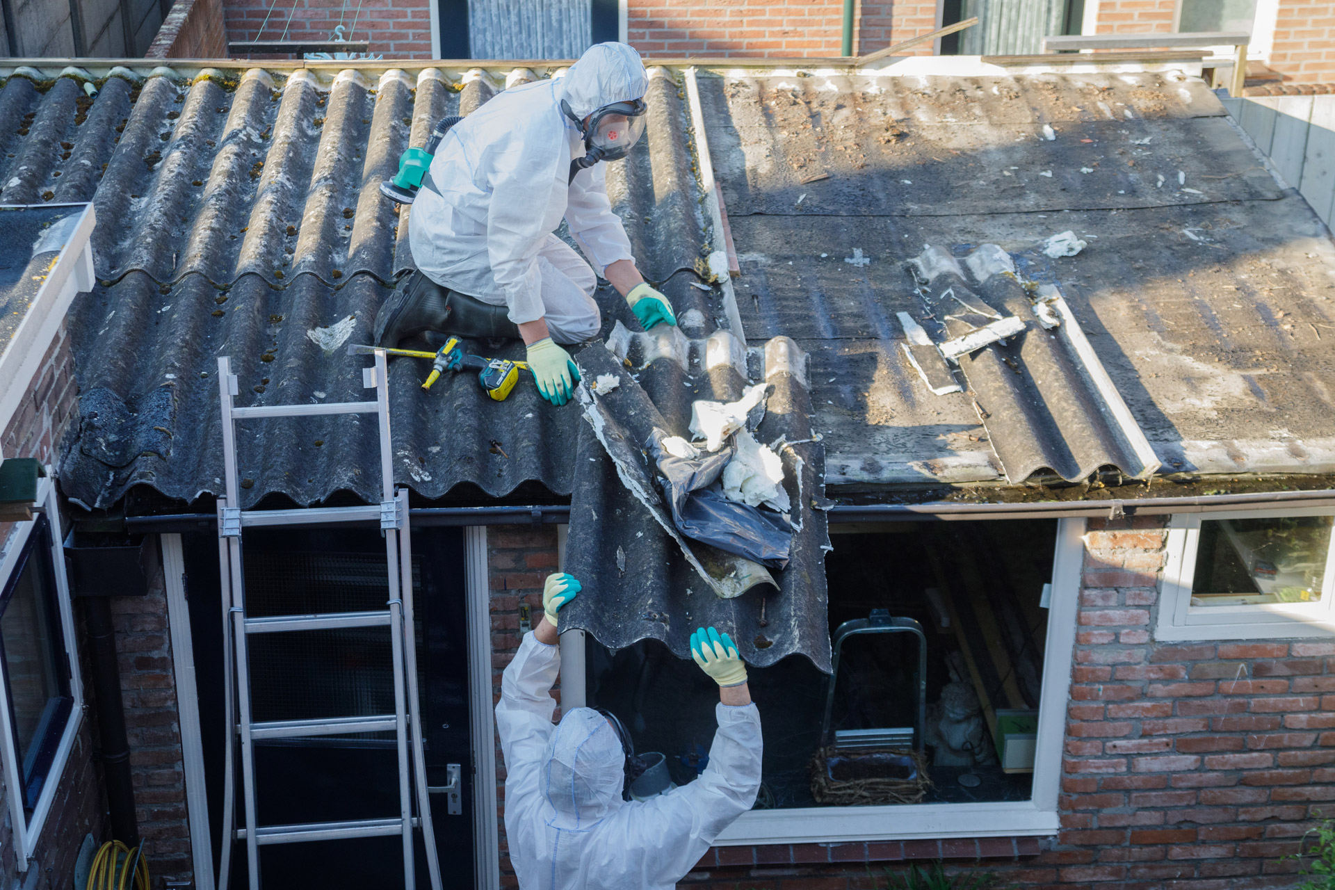 2 pracowników demontuje azbestowe pokrycie dachowe